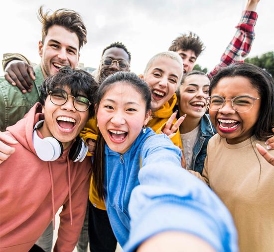 Group of happy college-age young adults taking a group selfie together